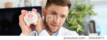 Portrait of male doctor holding a piggy bank on voluntary donations of money for a hospital or clinic 104048073