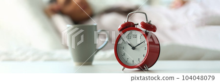 Red alarm clock at ten o'clock and sleeping woman 104048079