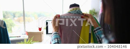 Woman fashion designer seamstress stylist measuring mannequin with tape Woman fashion designer seamstress stylist measuring mannequin with tape 104048146