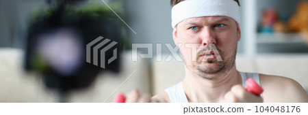 Athletic man doing physical exercises with dumbbells on camera 104048176
