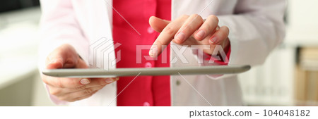 Female doctor is holding modern tablet and using remote telemedicine application 104048182