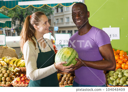 Man client is asking from seller female about freshness watermelon and melon 104048409