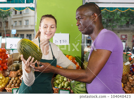 Man client is asking from seller female about freshness watermelon and melon 104048423