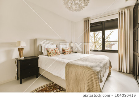 a bedroom with a bed and a chandel on the wall in front of the window that looks out onto the street 104050419