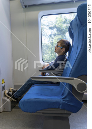 boy with glasses rides a commuter train, sitting at the window boy with glasses rides a commuter train, sitting at the window 104050745