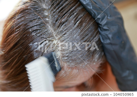A woman dyeing her gray hair with a brush A woman dyeing her gray hair with a brush 104050965