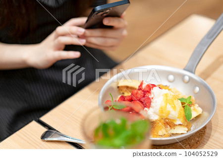 A woman taking a picture of cooking A woman taking a picture of cooking 104052529