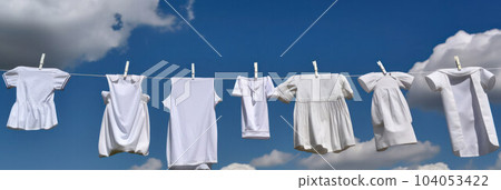 children's white clothes hanging on a rope on clothespins on the street against  104053422