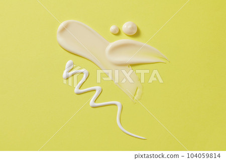 Creamy streaks of moisturizer, lotion, and sunscreen are displayed on a pastel green background. Minimal scene with space for design, advertising and branding cosmetic 104059814