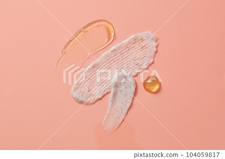 Creamy streaks with various renderings decorated on the pink background. Texture of scrubs, serums and essences. Top view and blank space for advertising and branding cosmetic 104059817