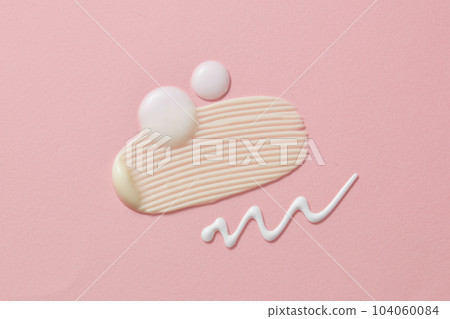 Cosmetic white smears and drops of cream or lotion on the pink background. Cosmetic skincare products texture Cosmetic white smears and drops of cream or lotion on the pink background. Cosmetic skincare products texture 104060084