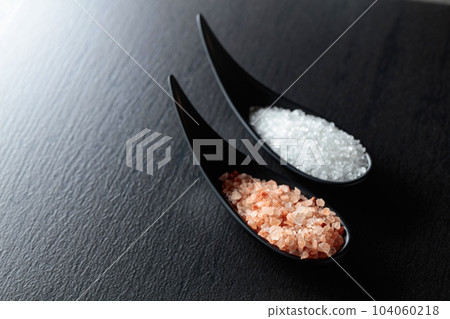 White sea salt and pink Himalayan salt on a black table. 104060218