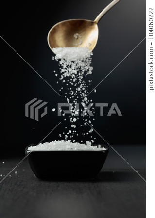 Sea salt is poured into a black bowl. 104060222