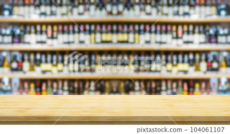 Empty wood table top with blur wine bottles on liquor alcohol shelves in supermarket wine store background 104061107