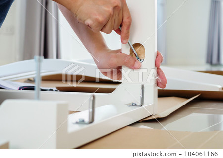 Man assembling white chair furniture at home 104061166
