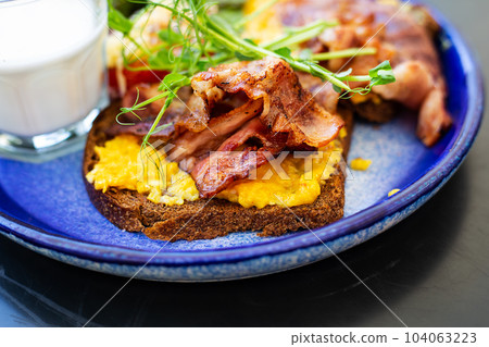 Very bright and healthy breakfast on a plate - bacon, egg, salad, tomato, cheese, a glass of yogurt. Close-up. Very bright and healthy breakfast on a plate - bacon, egg, salad, tomato, cheese, a glass of yogurt. Close-up. 104063223