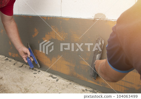 A building contractor is installing a reinforcing mesh A building contractor is installing a reinforcing mesh 104063499