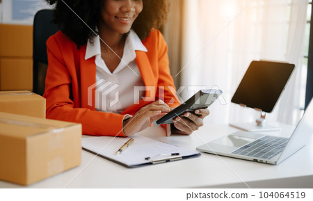 Young woman holding a smartphone showing payment success and credit card with yellow parcel box as online shopping concept  in home office. 104064519