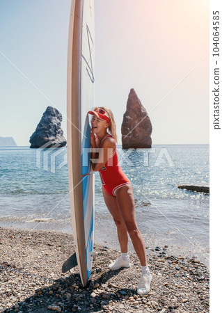 Woman sea sup. Close up portrait of happy young caucasian woman with blond hair looking at camera and smiling. Cute woman portrait in red bikini posing on sup board in the sea Woman sea sup. Close up portrait of happy young caucasian woman with blond hair looking at camera and smiling. Cute woman portrait in red bikini posing on sup board in the sea 104064585