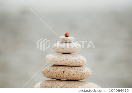 Calm pebble beach with pyramid stones and warm sunset on the sea background. Perfect travel destination for happy holidays, meditation, and relaxation at spa. concept of calmness and tranquility. Calm pebble beach with pyramid stones and warm sunset on the sea background. Perfect travel destination for happy holidays, meditation, and relaxation at spa. concept of calmness and tranquility. 104064615