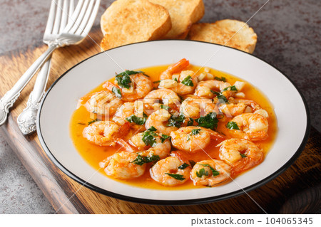 Fried shrimp with garlic and hot peppers in fragrant olive oil close-up on a wooden board. horizontal 104065345