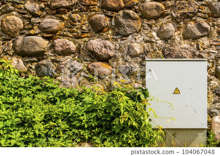 Electrical control cabinet against a rough stone wall Electrical control cabinet against a rough stone wall 104067048