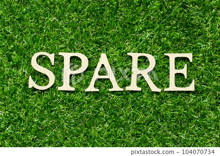 Wood letter in word spare on green grass background Wood letter in word spare on green grass background 104070734