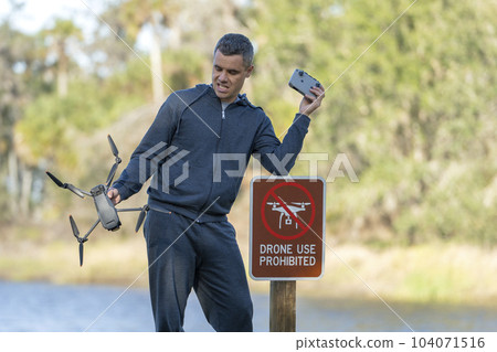 Drone operator is disappointed because he isn't allowed to fly his quadcopter in national park no drone area. Man is unable to use his UAV near restriction notice sign. Airspace use regulations 104071516