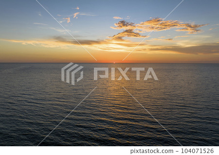 Dramatic bright red sky at ocean sunset, soft evening clouds over sea dark water 104071526