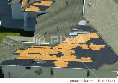 Damaged house roof with missing shingles after hurricane Ian in Florida. Consequences of natural disaster Damaged house roof with missing shingles after hurricane Ian in Florida. Consequences of natural disaster 104071573