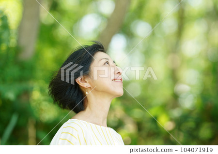 綠意中,白髮隨風飄揚的中年婦女 綠意中,白髮隨風飄揚的中年婦女 104071919