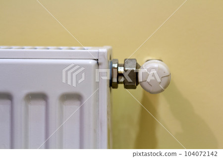 Close-up of white heating radiator with thermostat valve on light wall copy space background. Comfortable warm home interior, climate control, money saving concept. 104072142