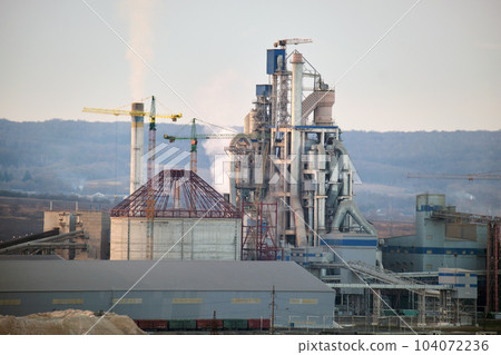 Cement plant with high factory structure and tower cranes at industrial production area. Manufacture and global industry concept 104072236