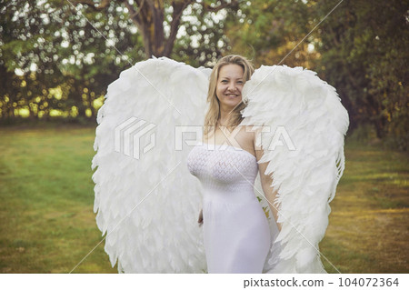Beautiful woman dressed as an angel in the evening garden 104072364