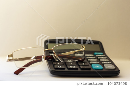 Calculator with glasses on white background. Tax concept Calculator with glasses on white background. Tax concept 104073498