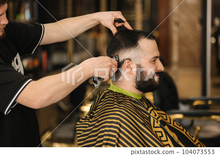 Side view of Professional barber cutting hair of his client. Side view of Professional barber cutting hair of his client. 104073553