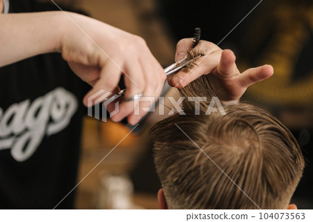 Back view of barber using scissors and making hairstyle. Modern barbershop Back view of barber using scissors and making hairstyle. Modern barbershop 104073563