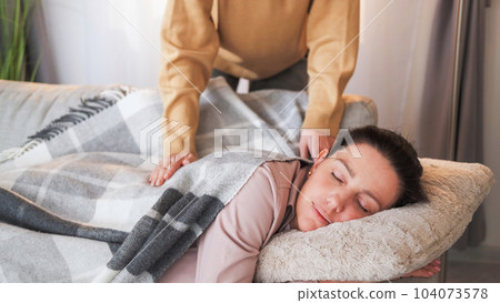 Home nap. Caring daughter. Loving unrecognizable girl covering plaid mother sleeping on sofa weekend drowsing in light room interior. Home nap. Caring daughter. Loving unrecognizable girl covering plaid mother sleeping on sofa weekend drowsing in light room interior. 104073578