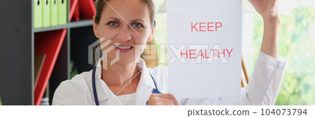 Smiling woman doctor shows inscription keep patient healthy 104073794