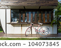 A pink bicycle is parked at the entrance of a cafe with a welcome sign 104073845