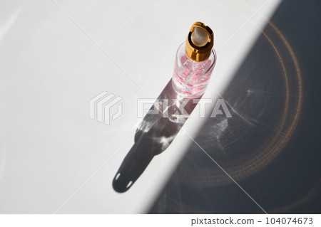 Cosmetic product bottles with rose petals and hard shadow. Skincare beauty product concept Cosmetic product bottles with rose petals and hard shadow. Skincare beauty product concept 104074673