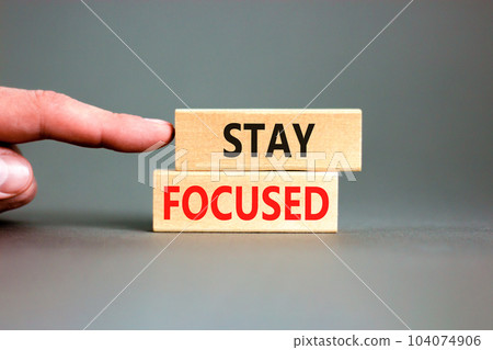 Stay focused symbol. Concept words Stay focused on wooden blocks on a beautiful grey background. Businessman hand. Business, support, motivation, psychological and stay focused concept. Copy space. 104074906