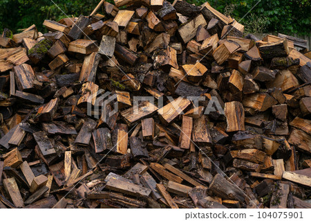 Wooden natural cut logs different sizes stored for fuel in countryside. Textured background. Wooden natural cut logs different sizes stored for fuel in countryside. Textured background. 104075901