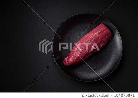 Juicy raw beef with spices, salt and herbs on a dark concrete background Juicy raw beef with spices, salt and herbs on a dark concrete background 104076871