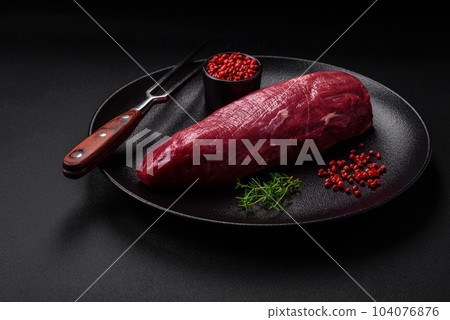 Juicy raw beef with spices, salt and herbs on a dark concrete background 104076876