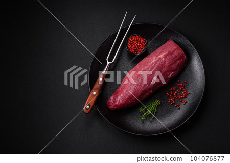 Juicy raw beef with spices, salt and herbs on a dark concrete background 104076877