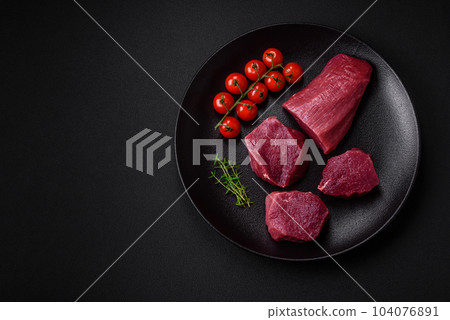 Juicy raw beef with spices, salt and herbs on a dark concrete background Juicy raw beef with spices, salt and herbs on a dark concrete background 104076891