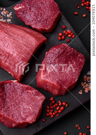 Juicy raw beef with spices, salt and herbs on a dark concrete background Juicy raw beef with spices, salt and herbs on a dark concrete background 104076915