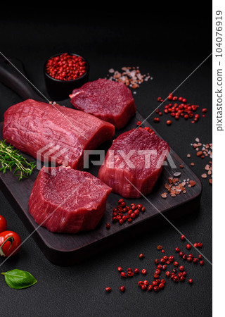 Juicy raw beef with spices, salt and herbs on a dark concrete background 104076919