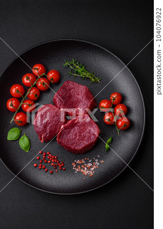 Juicy raw beef with spices, salt and herbs on a dark concrete background 104076922